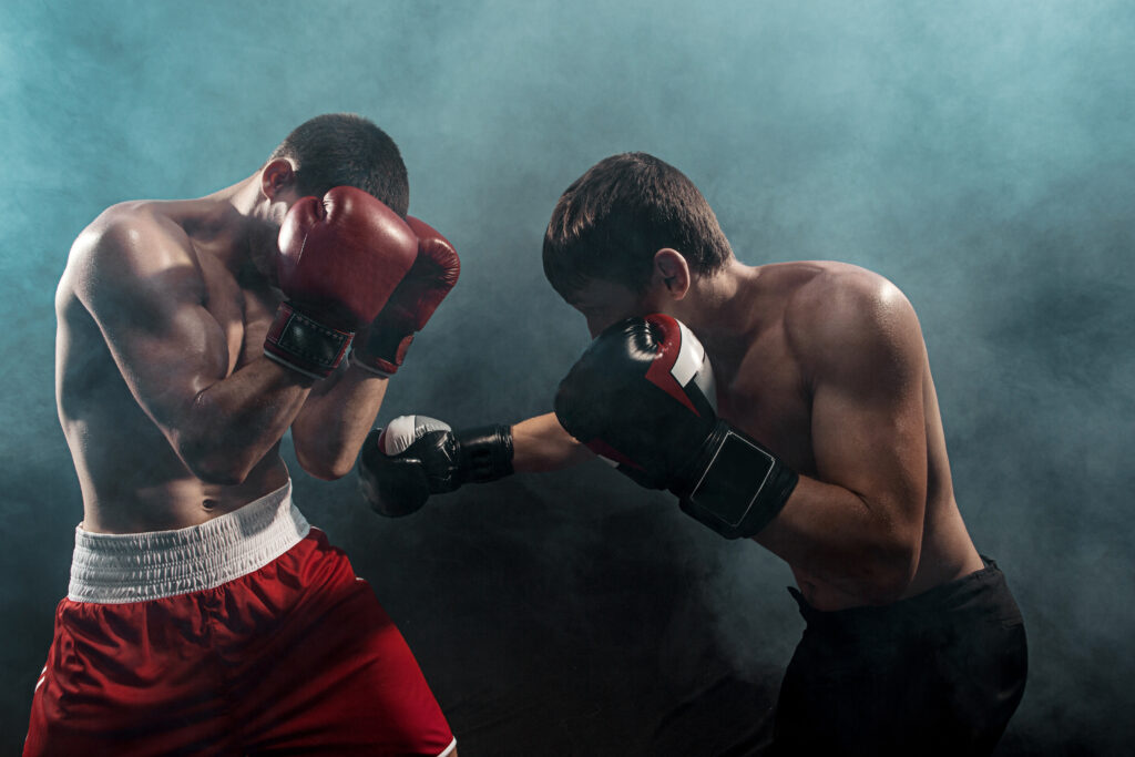Two professional boxer boxing on black smoky studio background.